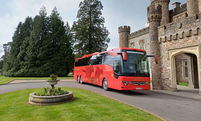 A red coach parked outside castle entrance